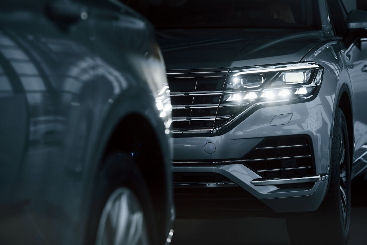 Powerful headlights. Particle view of modern luxury cars parked indoors at daytime.
